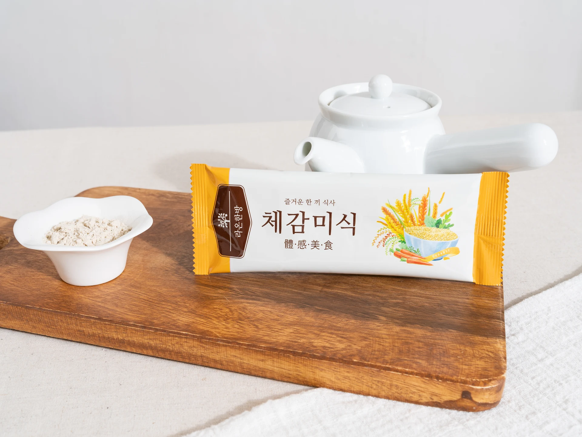 나무 보드 위에 놓인 체감미식 포장과 분말이 담긴 스푼